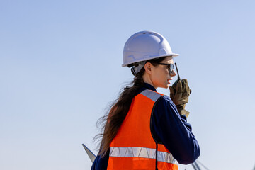 group of industrial engineers workers in a refinery - oil and gas processing equipment and machinery, engineers collaborate with a laptop, blueprint, and digital tablet at the oil storage tanks site.