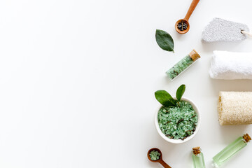 Obraz na płótnie Canvas Spa pedicure accessories and organic cosmetics products - tea tree essential oil and sea salt near green leaves top view