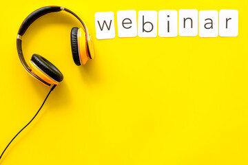 Webinar word on paper cards. Headphones on yellow table workspace, top view