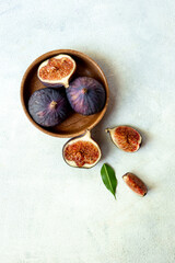 Fresh ripe figs on a wooden bowl top view on a stone background