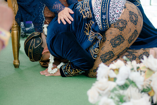 Close-up of a groom performing the traditional Javanese Sungkeman ritual to seek parents' blessing.