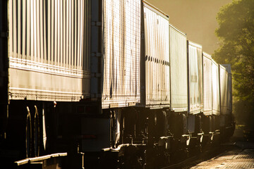 Truck trailers on train cars compressed view at sunset