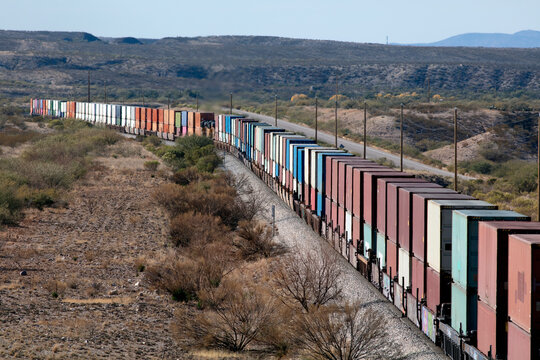 Long train of container stacks in rural country landscape