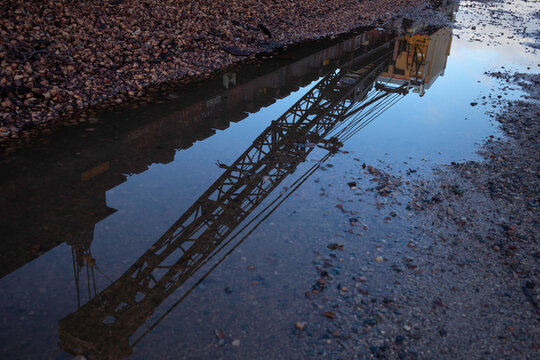 Reflection of crane boom in rain puddle