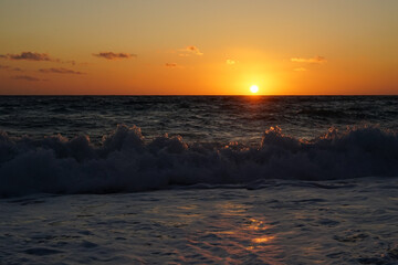 Beautiful sunset or sunrise on the beach with stones and rough sea in Cyprus
