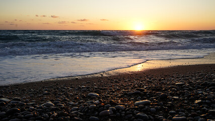 Beautiful sunset or sunrise on the beach with stones and rough sea in Cyprus