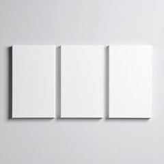 Fototapeta premium Three blank white canvases mounted on a light gray wall