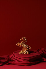Golden horse statue on red fabric podium. Lunar New Year 2026 symbol