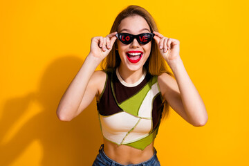 Smiling young woman with sunglasses displaying love message on a vibrant yellow background,...