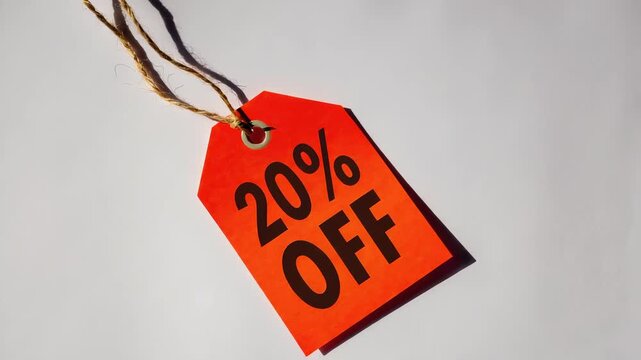 Red gift tag with twine hanging against a white background, perfect for holiday promotions, sales, or gift-giving concepts.