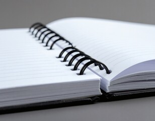 Close-up of an open spiral-bound notebook with lined paper on a gray surface, against a plain gray background.