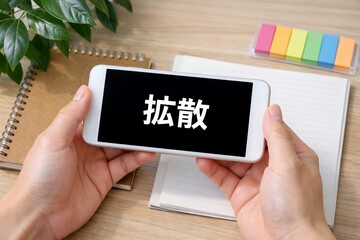 拡散と表示されたスマートフォンを両手で持ち情報が広がる様子を表現したイメージ