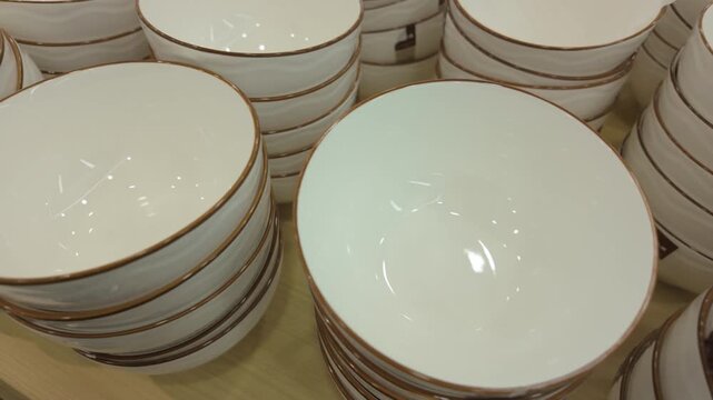 Large quantities of gold edged white porcelain bowls are piled up