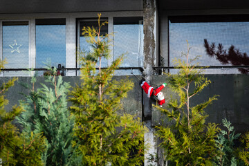 Eine Weihnachtsmann Figur h&auml;ngt an einem Betonbalkon hinter Tannen, Wuppertal, Deutschland