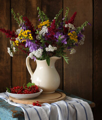 summer still life with a bouquet of wild flowers and red currants in rural style