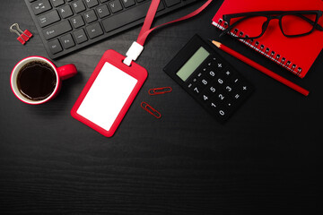 Red plastic badge with stationery and coffee on black wooden texture background. Template designed for employees of company