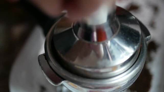 close up to hand using coffee tamper stamp into coffee Portafilter bucket full with grounded coffee bean to make espresso for morning hot beverage drink, coffee brew morning drink