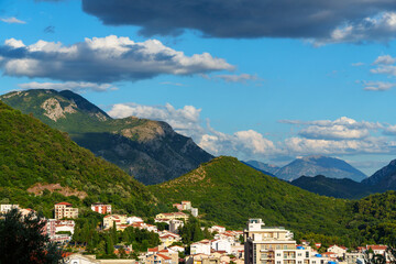 Obraz premium panoramic view of forested mountains and small resort town of Petrovac below, Montenegro, beautiful landscape