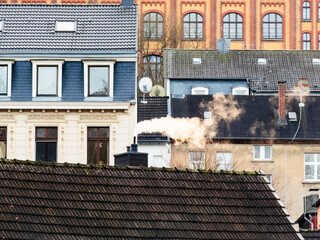 Rauch oder Wasserdampf steigt aus einem Schornstein in einem dicht bebautem Wohnviertel in Wuppertal, Deutschland