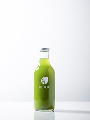 Green detox juice in glass bottle on minimalist white background  