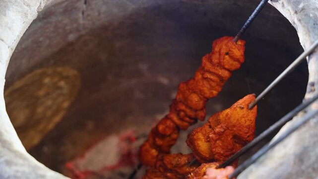 spicy chicken tikka cooking in tandoor with glowing charcoal