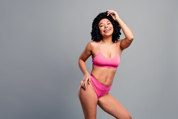 Confident young woman in pink bikini posing for fitness and lifestyle shoot smiling and enjoying moment