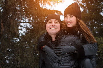 Joyful Holiday Embrace, Happy Partners Embracing Amidst Festive Background With Sunlight Shining, Coupled Individuals Showing Affection During Holiday Season With Evergreen Trees And Sun Flare