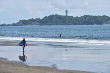 潮が引いた片瀬西浜海岸で海に入るサーファー