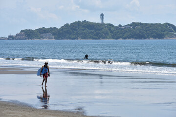 潮が引いた片瀬西浜海岸で海に入るサーファー