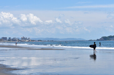 潮が引いた片瀬西浜海岸で海に入るサーファー
