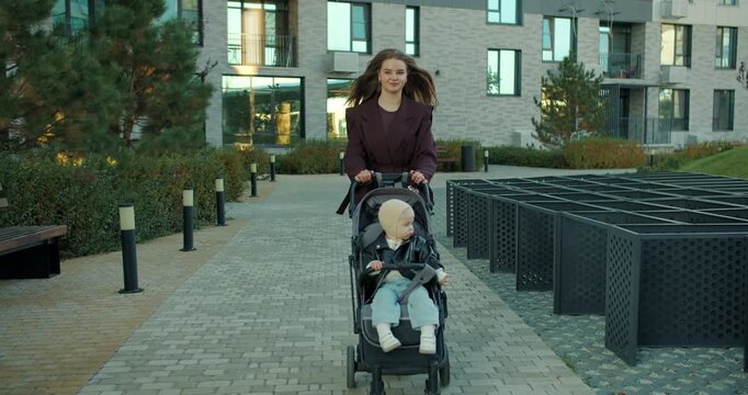 Mother pushing stroller with toddler in modern residential courtyard