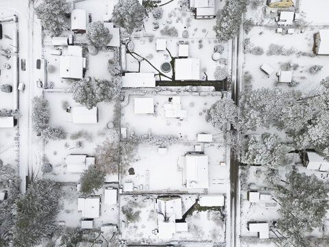 Aerial view of snow-blanketed houses and trees, transforming the landscape into a serene winter wonderland, Bestensee, Brandenburg, Germany.