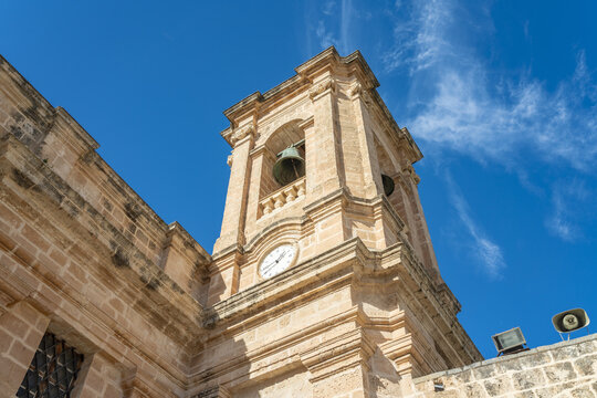 View of Parish Church of Mellieha, with its bell tower and red-domed roof standing out against the stark blue sky, Mellieha, Malta.