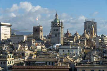 View of sun-kissed rooftops and historic towers rise against a backdrop of cerulean skies, showcasing the timeless beauty of the Italian city, Genoa, Liguria, Italy.