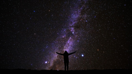 Silhouette of a woman and countryside under Milky Way stars and planets. © astrosystem
