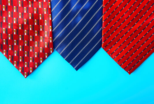 Three patterned neckties on blue background with copy space