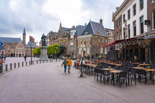 Haarlem, Netherlands - 06 May 2019: View of the Grote Markt square's cobblestone expanse, lined with historic buildings, cafes, and the imposing Stadhuis under a cloudy sky.