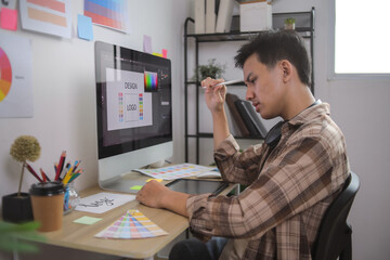 Man Smiling and Actively Working on Branding, Using Graphic Tablet and Surrounded by Design Charts