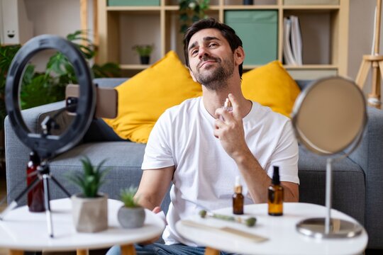 Man spraying perfume and creating lifestyle content at home studio