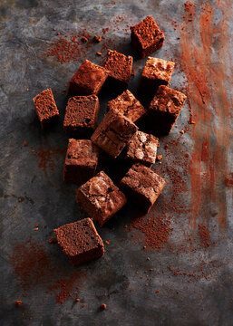 Chocolate brownies with cocoa dusting on dark rustic background
