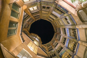 Barcelona, Spain - 08 November 2016: View of the building's inner courtyard, with its warm, earthy tones contrasting against the deep, dark sky above.