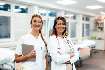 Nurse and doctor smiling in hospital ward with digital patient record