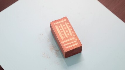 Wooden block with engraved pattern evolving on a light blue surface. Hobby or craft concept for artistic design.