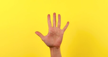 Close-up of a woman’s hand counting from one to five on fingers against a bright yellow background. Minimalist 4K video ideal for education, numbers, steps, progress, or presentation concepts.