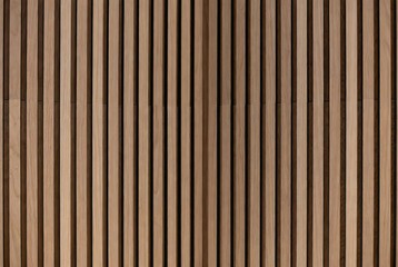 Fototapeta premium Vertical wooden slat wall texture with natural light brown tones and prominent wood grain patterns, creating a modern interior design background.
