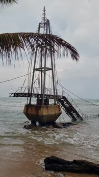 Vertical shot of the remains of the old Paravi Duwa Bridge in Matara, Sri Lanka, highlighting weathered concrete and rusted metal under an overcast monsoon sky