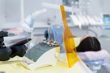 Dental bur kit and curing light shield on tray during pediatric dental treatment