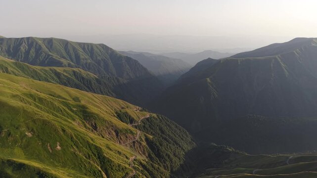 Aerial view of the winding road through the green Alazani pass, cutting a pale path through the landscape, Chala, Tusheti, Georgia.