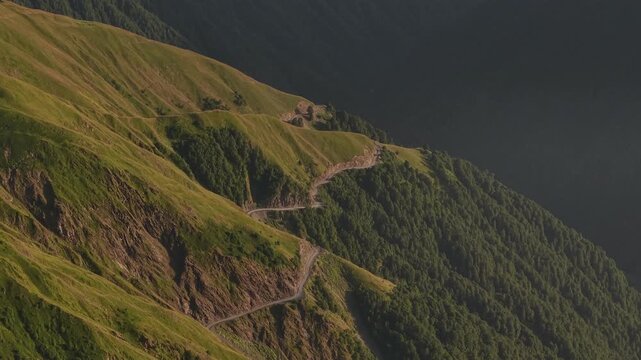 Aerial view of Alazani pass winding road cuts through the steep, lush green mountains, a testament to human ingenuity, Chala, Tusheti, Georgia.