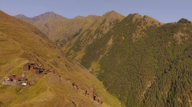 Aerial view of the Kvavlo village nestling amid rolling hills, its stone towers rising against the backdrop of the rugged Caucasus mountains, Dartlo, Tusheti, Georgia.